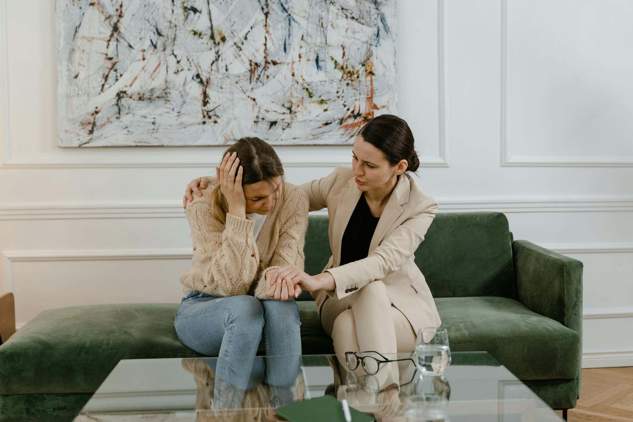 A therapy session where a concerned therapist supports a distressed woman in a modern office.